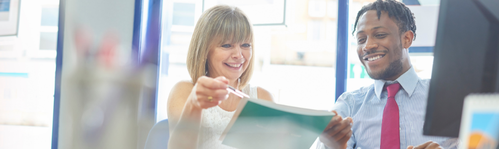 mature woman and young man looking over paperwork together, smiling