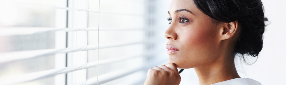 Black woman looking out window thoughtfully