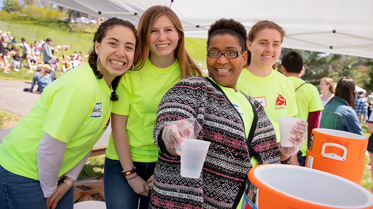 Group of employee smiling volunteers at Slope Day handing out glasses of water