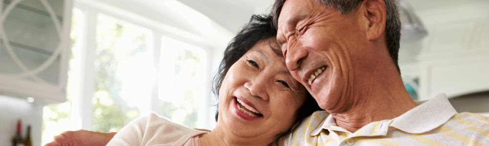 mature Asian couple smiling, looking off camera