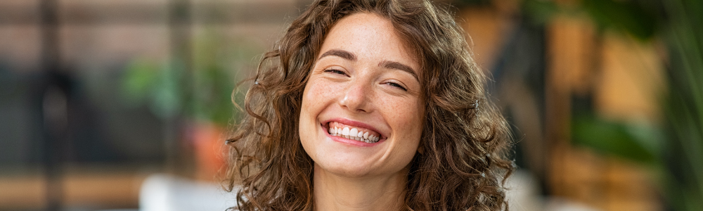 young woman with freckles smiling big smile