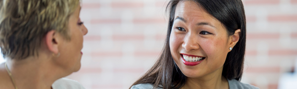 young Asian woman smiling at older woman in office setting