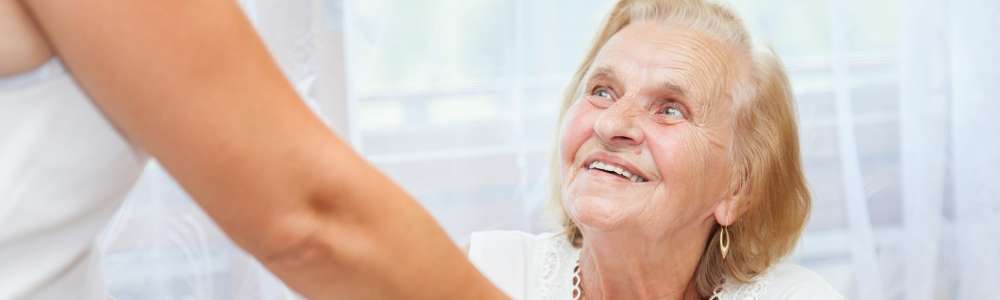 elderly woman looking up at caregiver, smiling