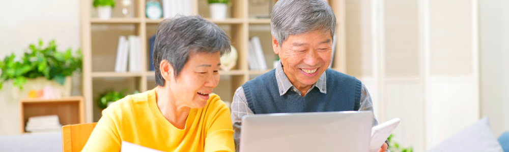 senior Asian couple smiling together at computer screen