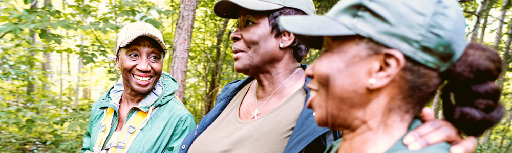 three senior Black women outdoors hiking and laughing