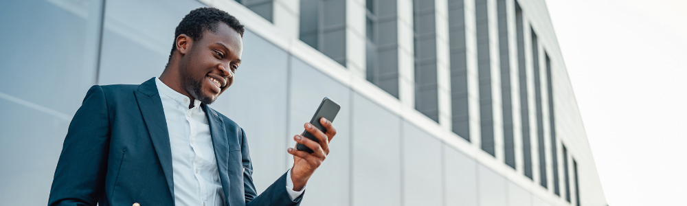 Black man smiling, reading something on phone