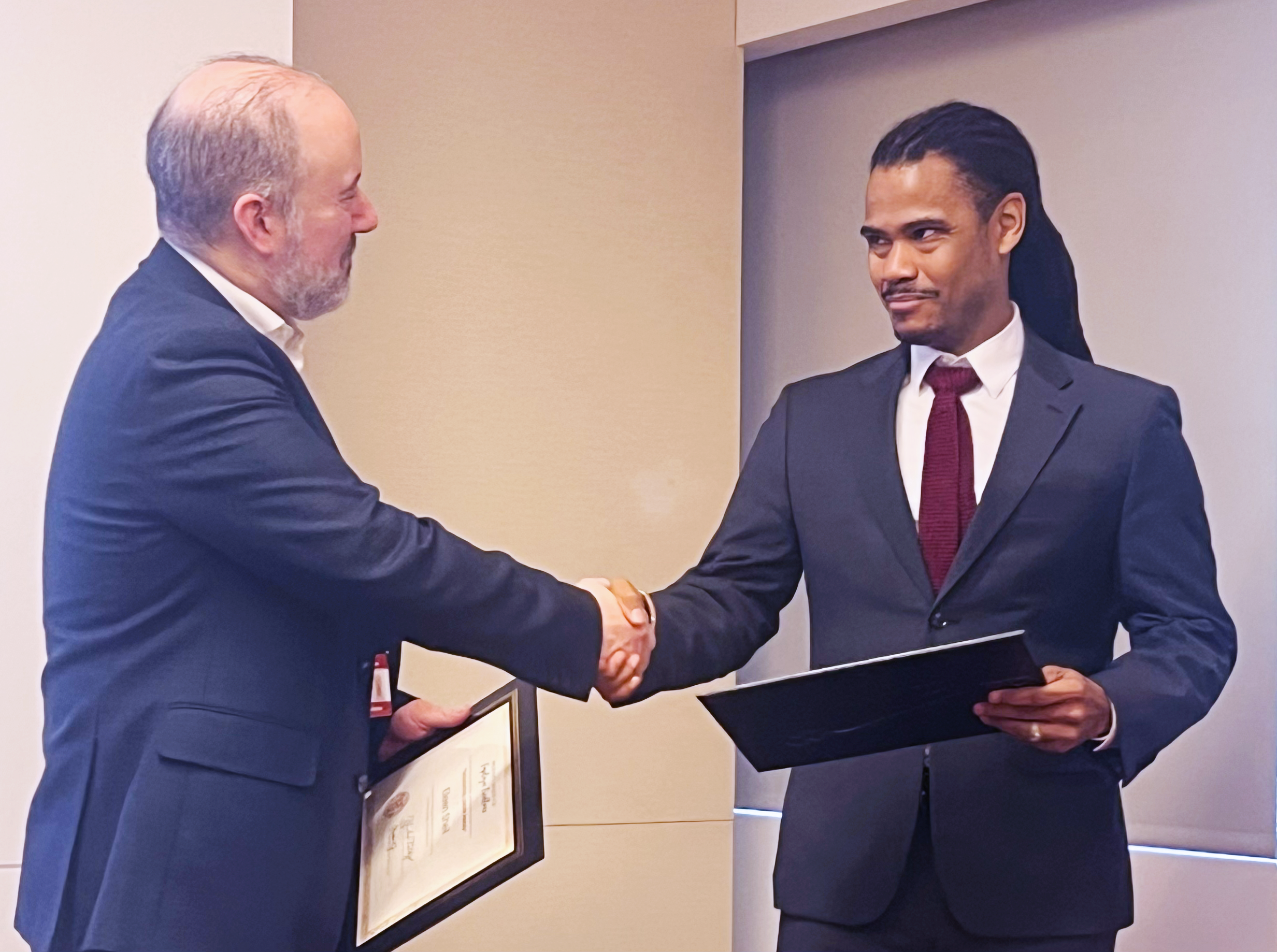 man shaking hands with another man, receiving award