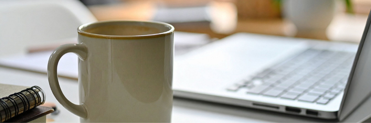 coffee cup on desk next to open laptop