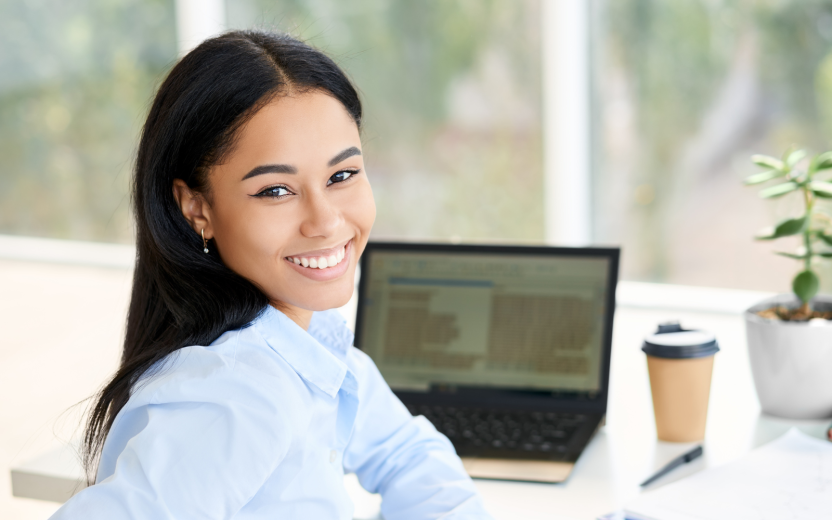 Young woman in front of laptop turning toward viewer smiling