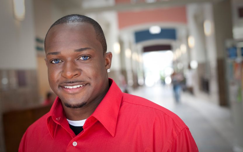 Young Black man in red shirt in hallway, smiling