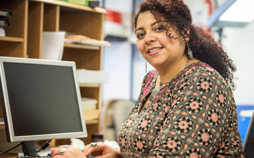 woman seated at desk with computer screen in office smiling