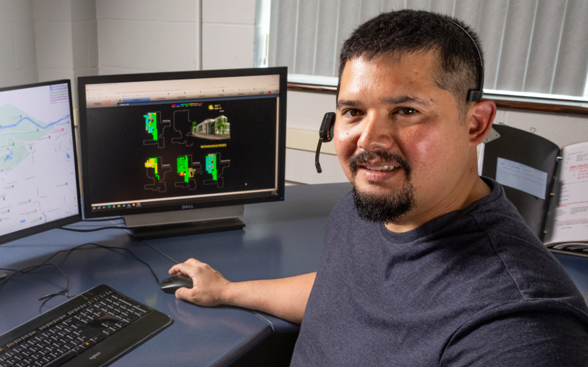 Carlos Ribellia seated in front of computer screens in office