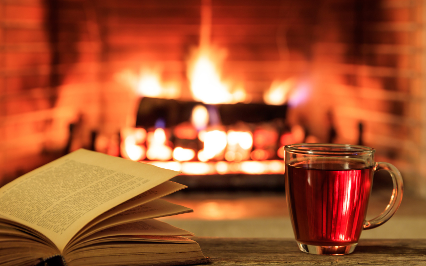 cozy fireplace with book and mug of spiced cider foreground