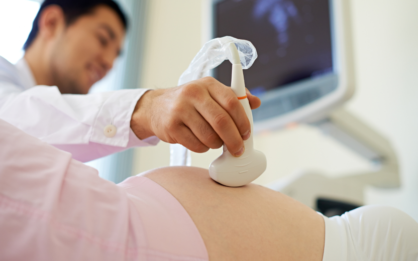 physician performing an ultrasound on pregnant person