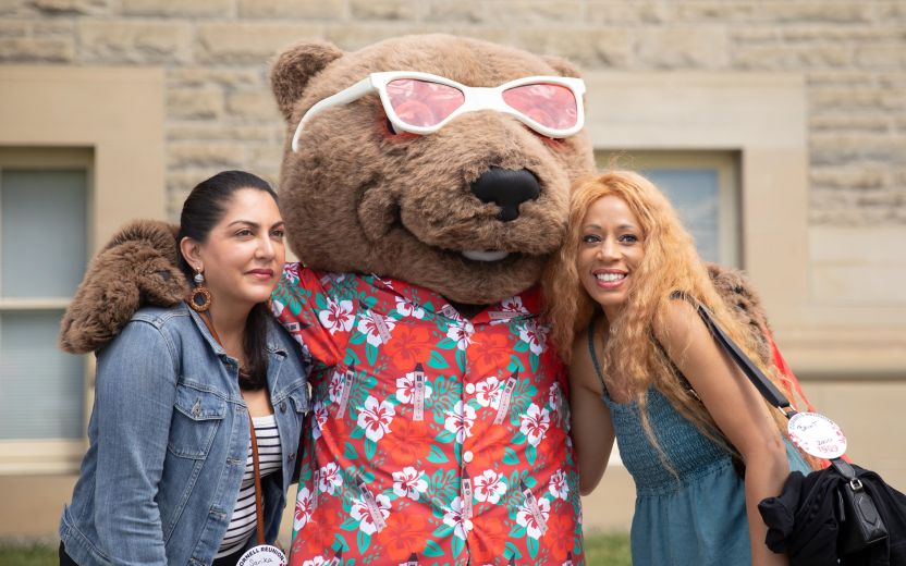 two women posing for photo with Touchdown bear