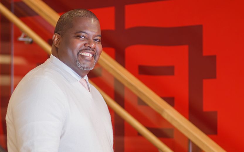 Kwesi Joseph next to stairs and cornell logo mural