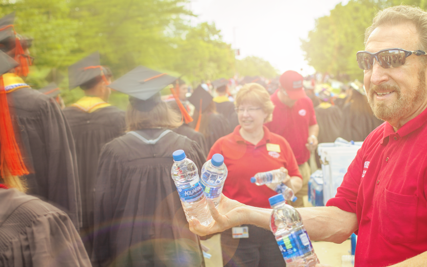 Cornell volunteer handing out water bottles to graduating students