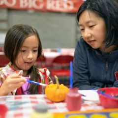 mother and daughter painting pumpkin
