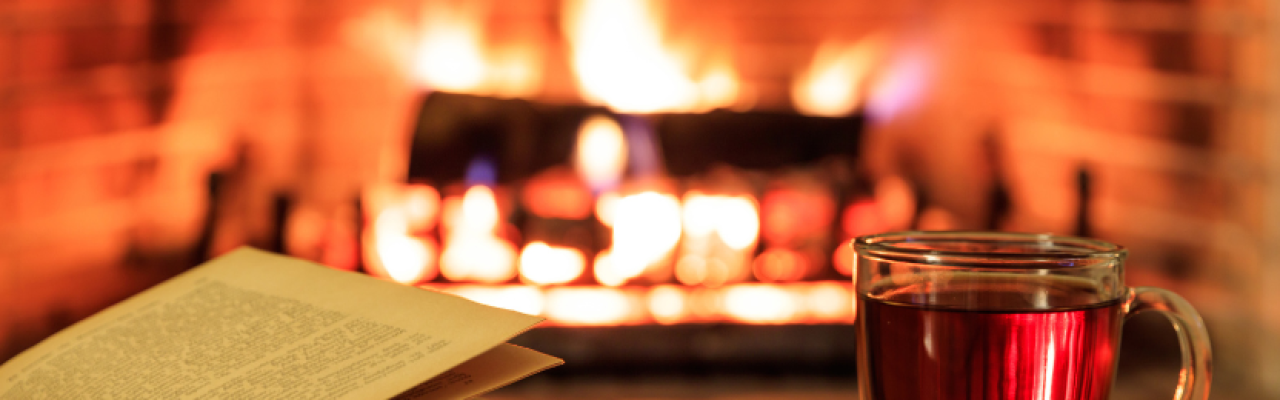 cozy fireplace with book and mug of spiced cider foreground