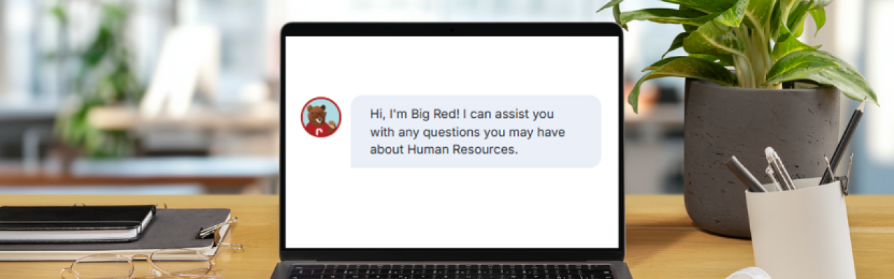 laptop on desk displaying chatbot opening: Hi, I'm Big Red! I can assist you with any questions you may have about Human Resources.